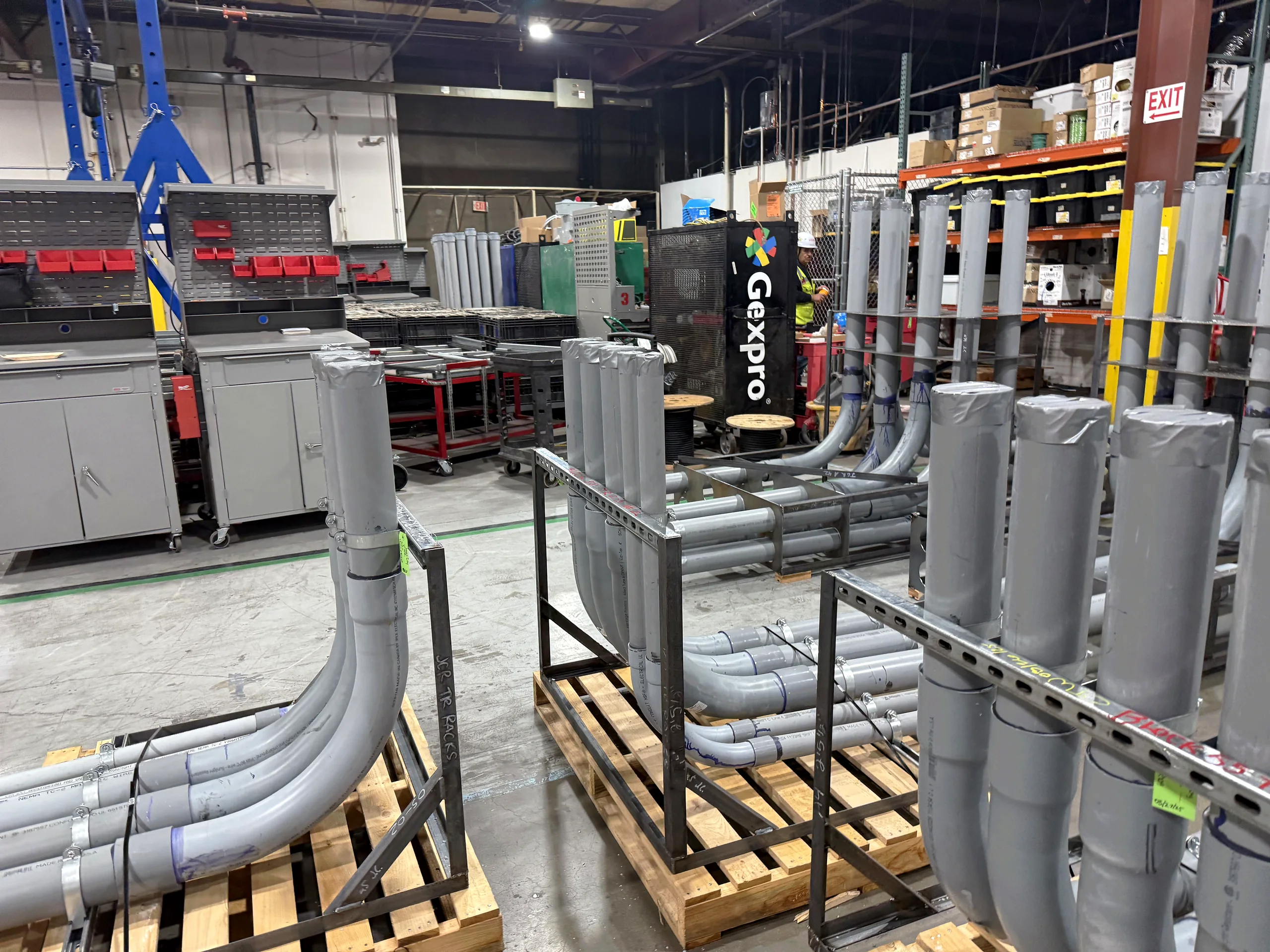 Racks of prefabricated electrical conduit assemblies staged on a plant floor