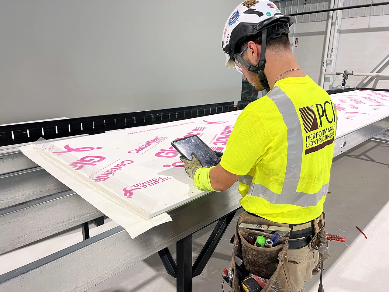 A PCI carpenter working a wall panel from a tablet on the prefab line